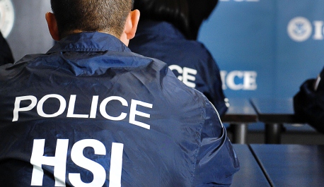 A police officer's back with "POLICE HSI" text.