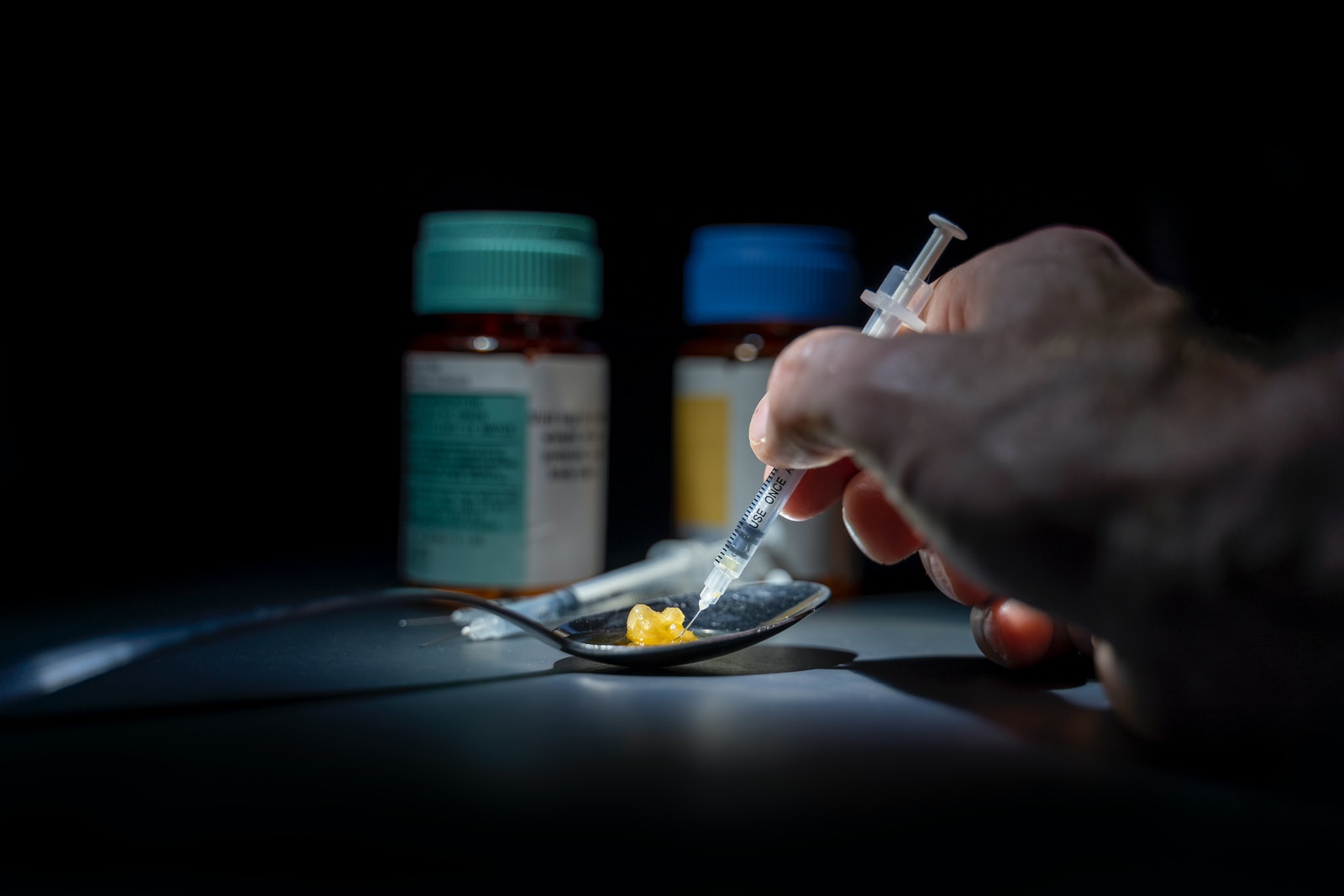 person using syringe on yellow stone on spoon