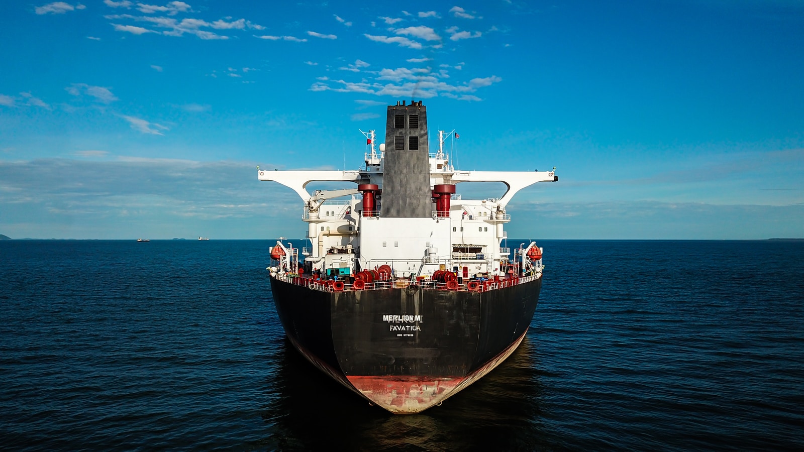 red and black ship on sea under blue sky during daytime