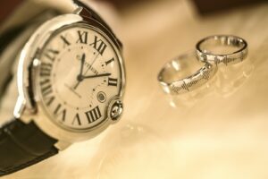 silver-colored analog watch near two silver-colored rings