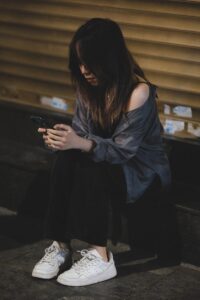 a woman sitting on the ground looking at her cell phone