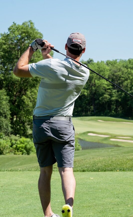 man in white t-shirt and black shorts playing golf during daytime